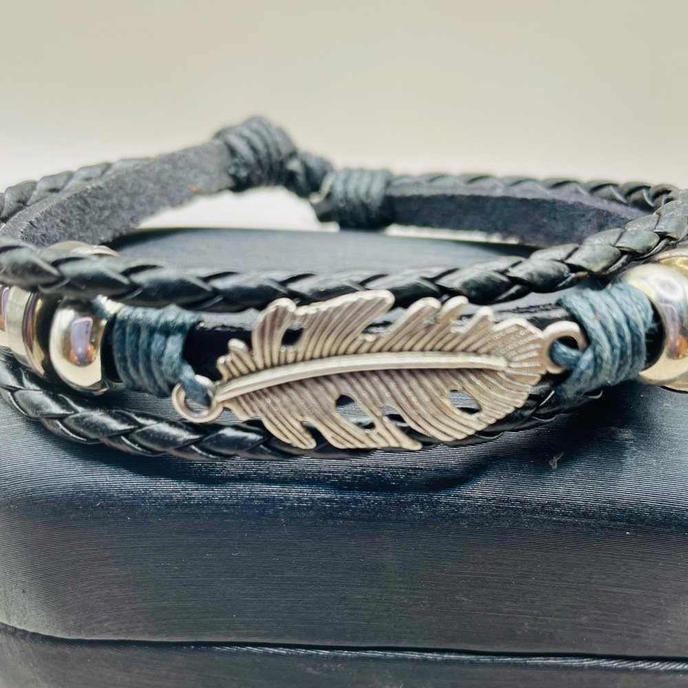 Feather leaf bracelet with black three row leather. One is braided. Adjustable